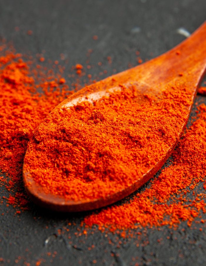 bottom-view-red-pepper-powder-wooden-spoon-dark-surface